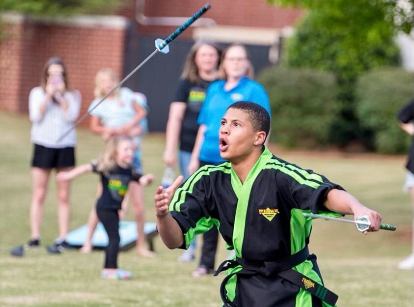Martial artist demonstrating a sword routine in the park